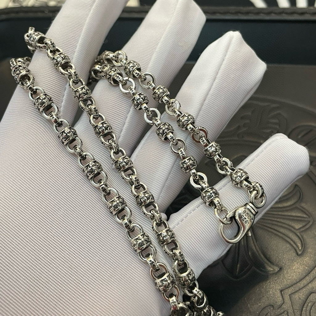 Set of metal chain necklaces on white display cushion
