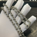 Set of metal chain necklaces on white display cushion