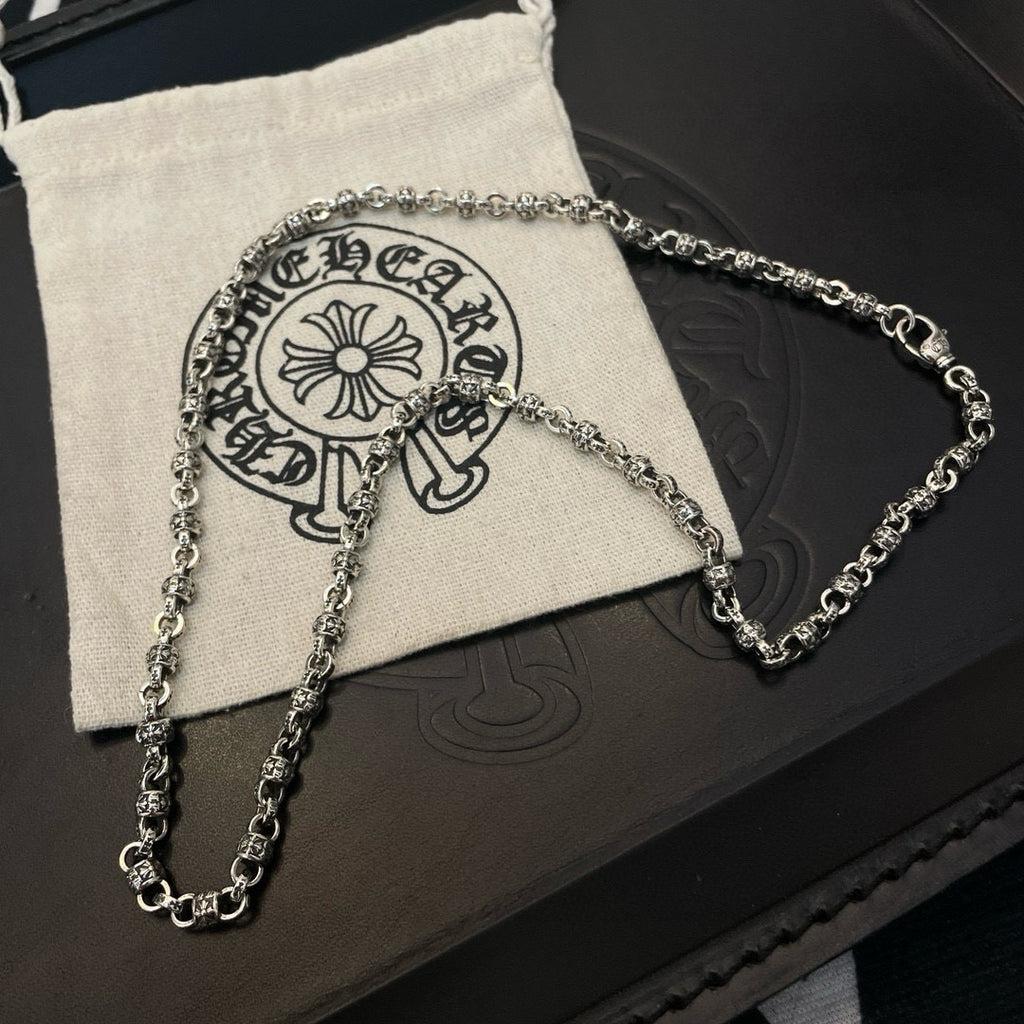 Metal chain necklaces on beige pouch over black jewelry box