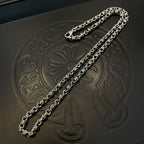 Two metal chain necklaces on black jewelry box surface