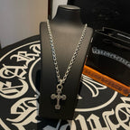 Cross pendant necklace on display bust with silver-toned chain and charm cross