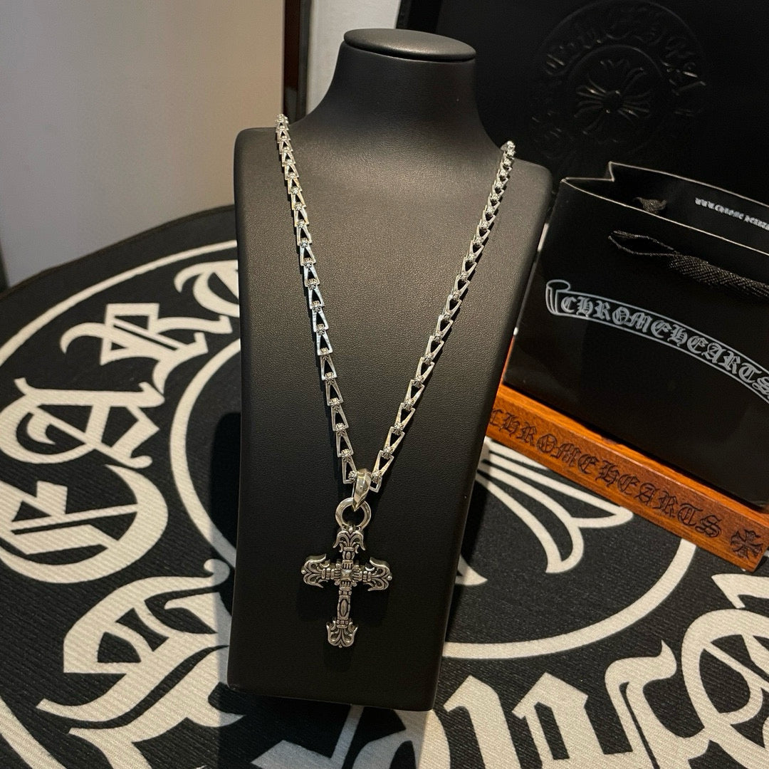 Cross pendant necklace on display bust with silver-toned chain and charm cross