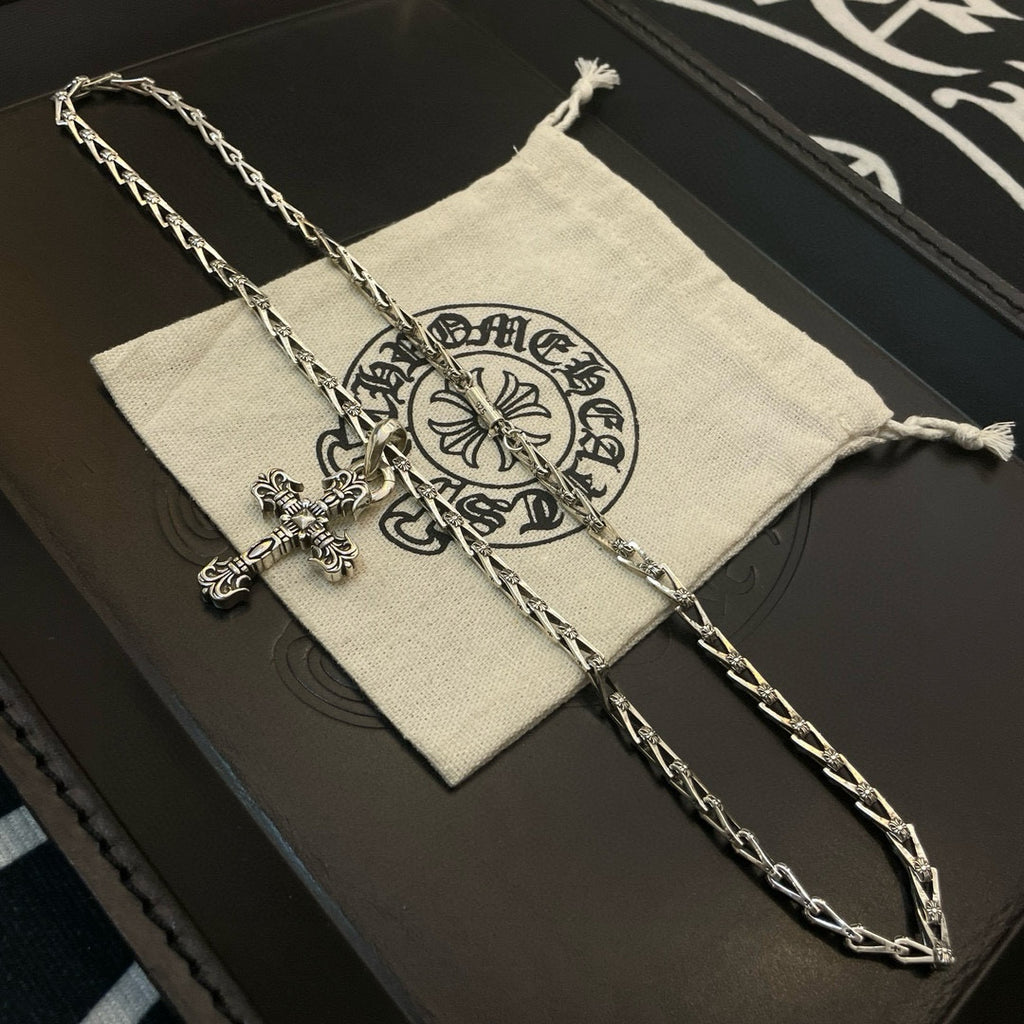 Silver-toned cross pendant necklace on a small cloth pouch inside a gift box