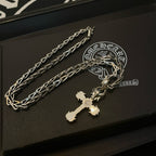 Cross pendant necklace with silver-toned chain and cross charm on a black box