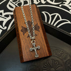 Cross pendant necklace with silver-toned chain hanging on a wooden box
