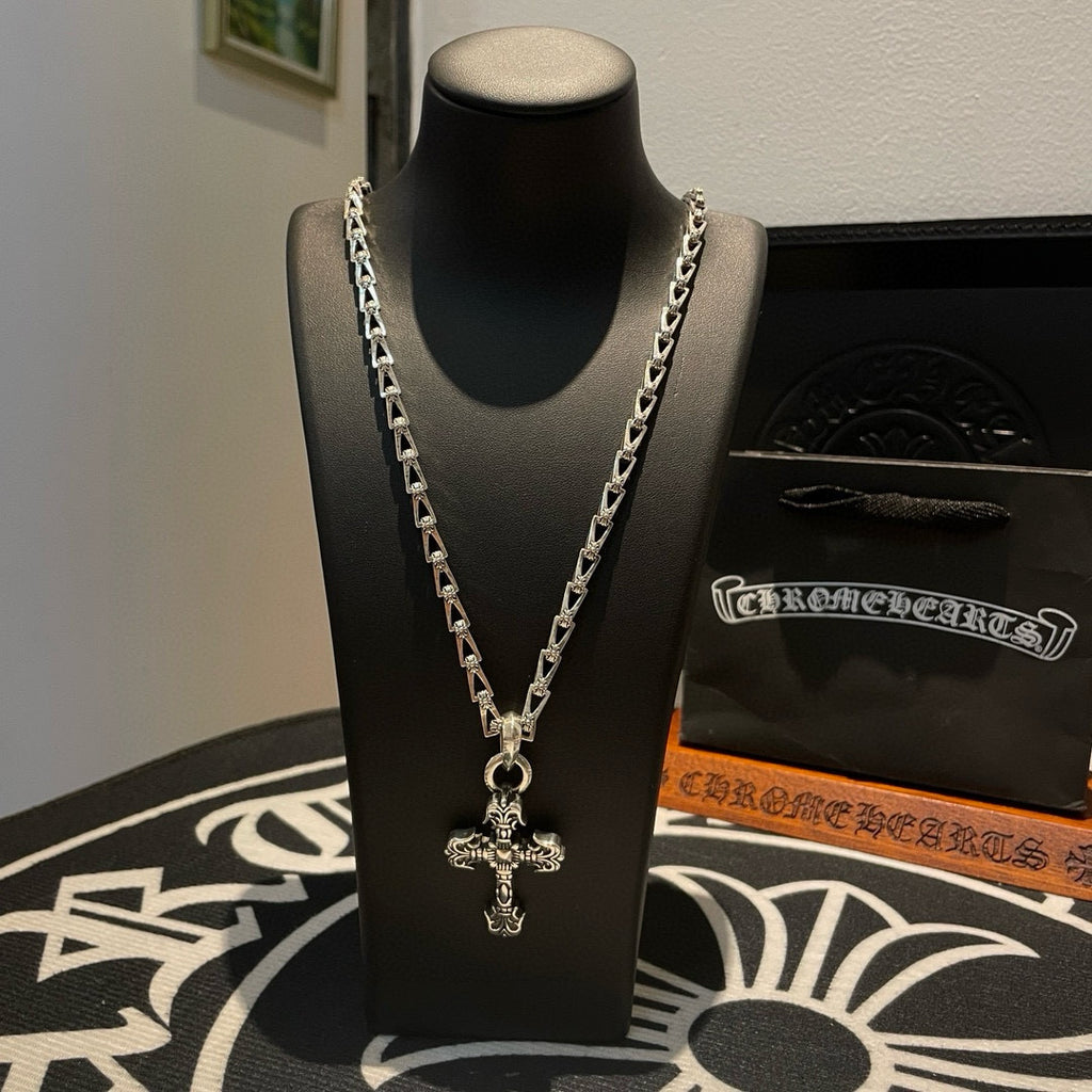 Cross pendant necklace with silver-toned chain on a black display bust