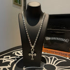 Cross pendant necklace with silver-toned chain on a black display bust