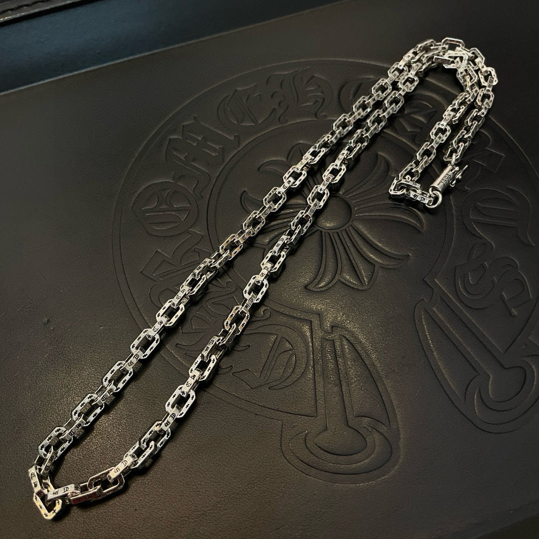 Silver-tone chain necklace with thick links on black leather tray.