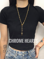 Gold chain cross pendant necklace worn over a black shirt