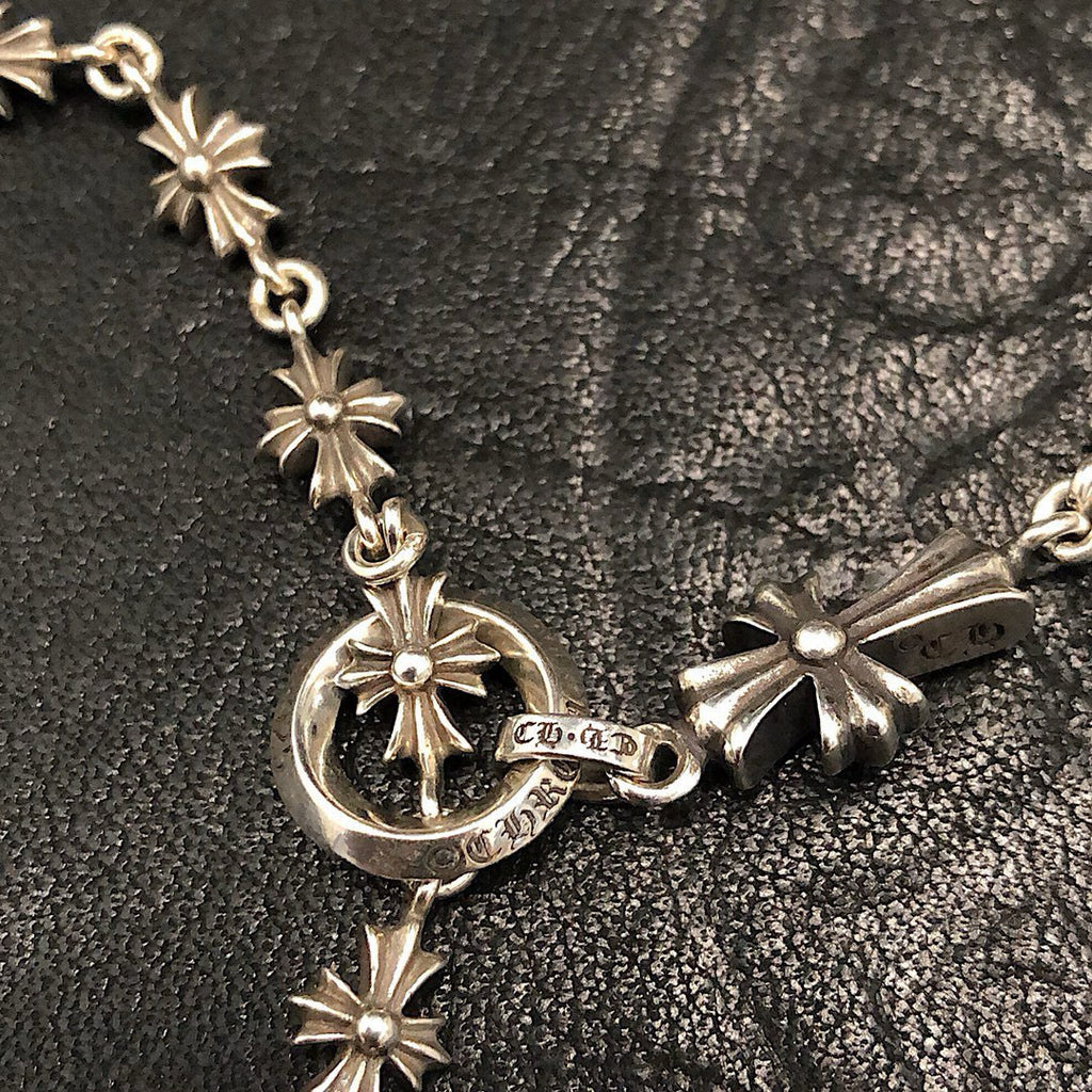 Silver chain necklace with starburst links and round charm at the clasp