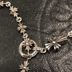 Silver chain necklace with starburst links and round charm at the clasp