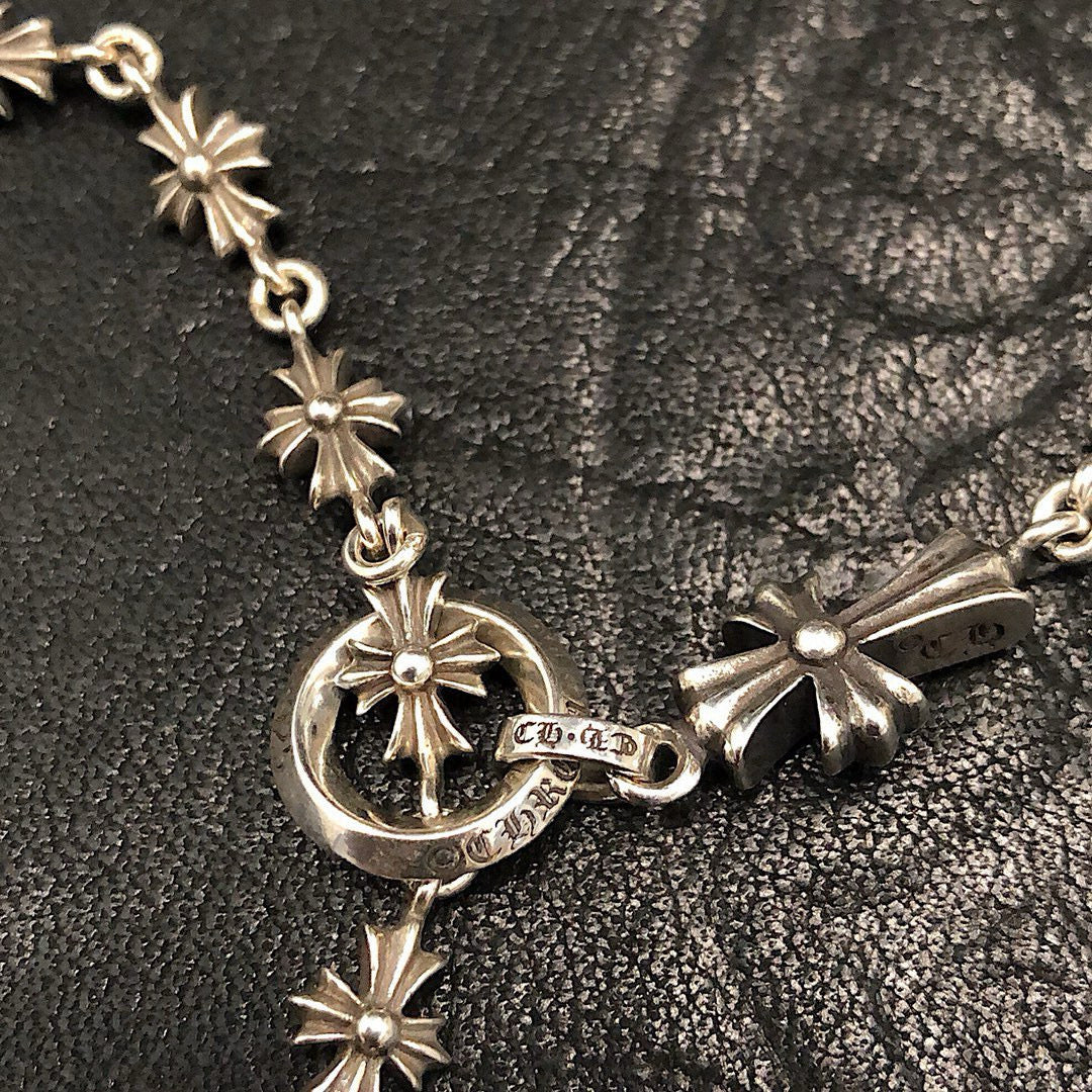Silver chain necklace with starburst links and round charm at the clasp