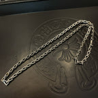 Silver-tone chain necklace close-up on embossed dark leather panel