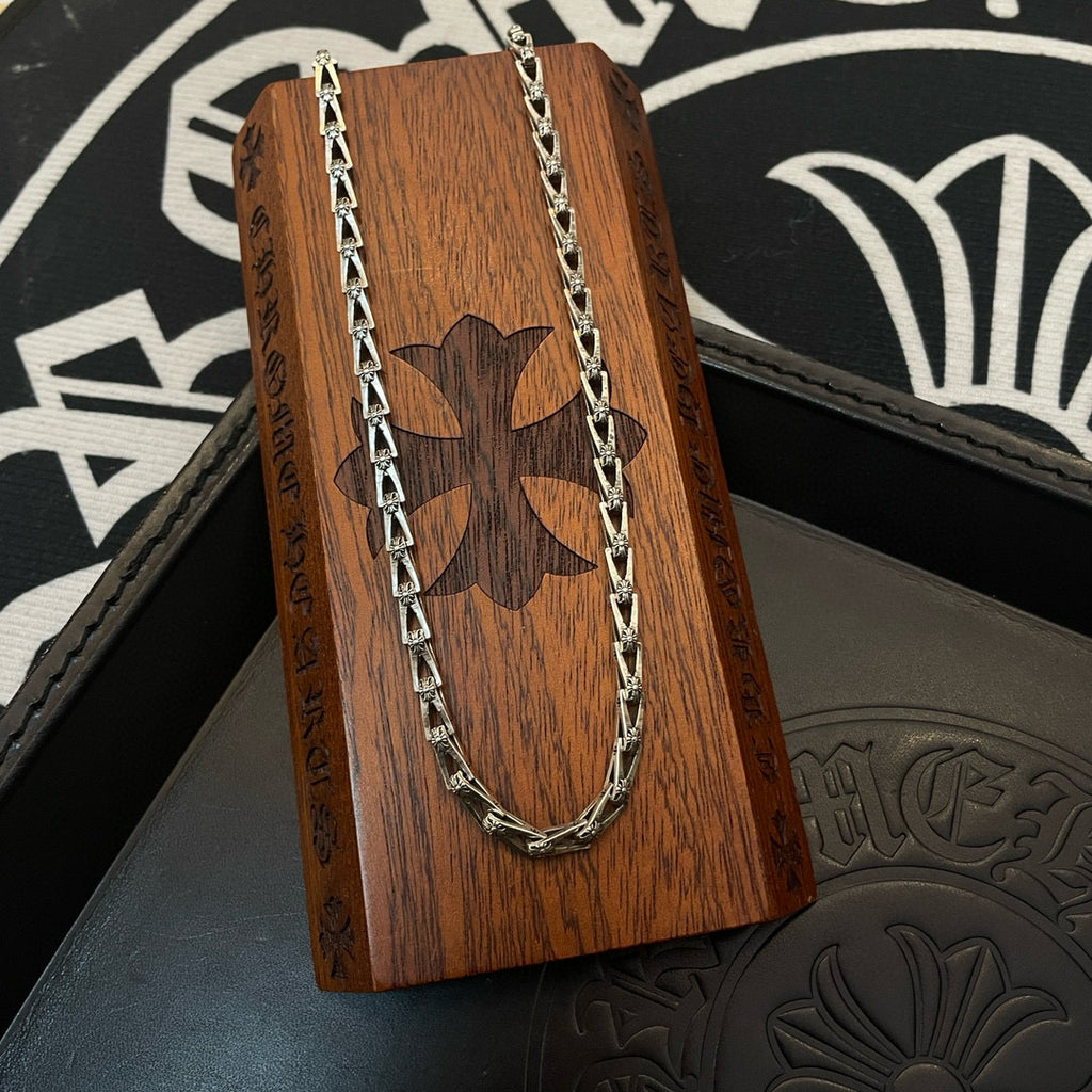 Silver-tone chain necklace draped over a brown wooden presentation stand