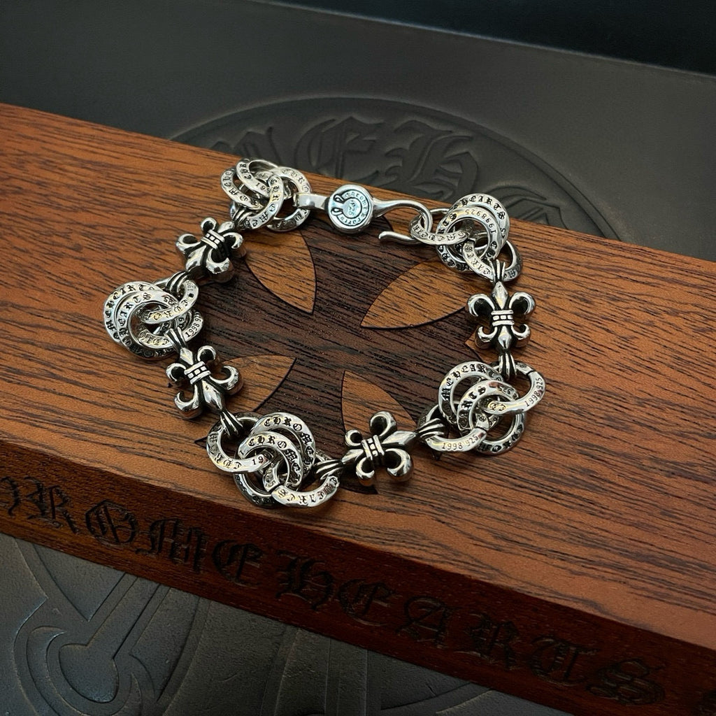 Silver-tone charm bracelet with oval links and dangling fleur-de-lis charms