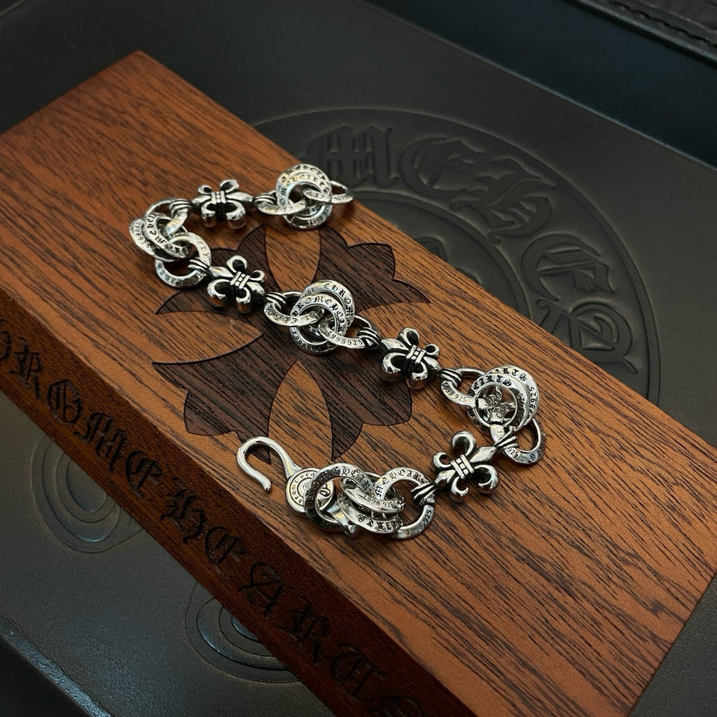 Silver-tone charm bracelet laid on wooden surface, clasp and medallion charms visible
