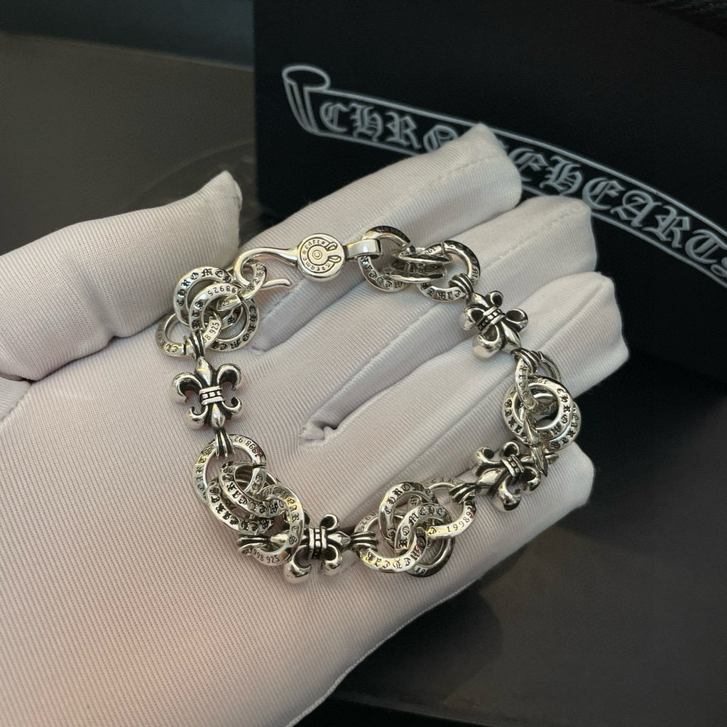 Silver-tone charm bracelet resting on white gloves, chain with round medallion charms
