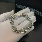 Silver-tone charm bracelet resting on white gloves, chain with round medallion charms