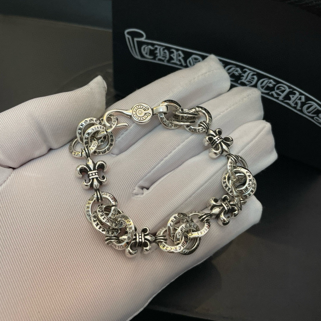 Silver-tone charm bracelet resting on white gloves, chain with round medallion charms