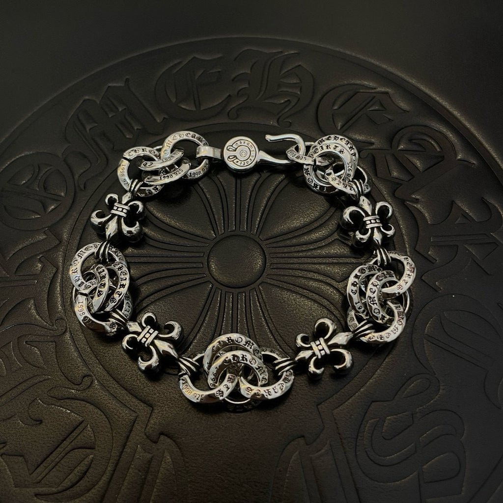 Silver-tone charm bracelet with oval links and decorative fleur-de-lis motifs