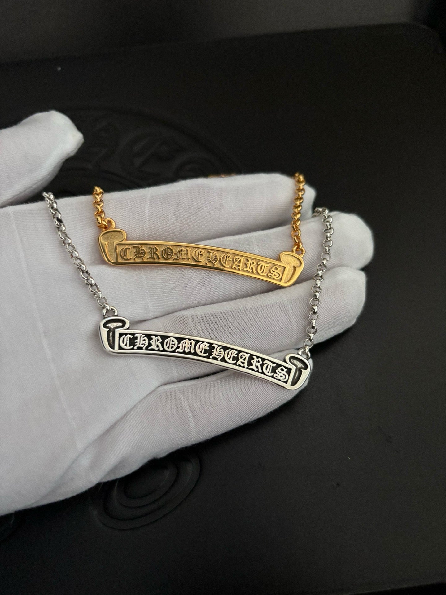 Gold- and silver-tone bar pendant necklaces held on a white glove