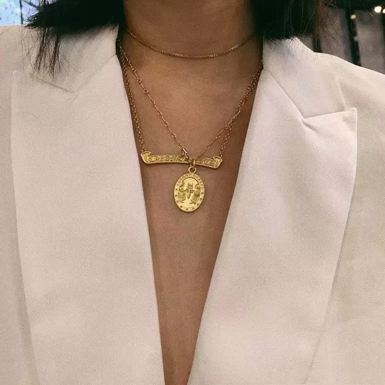 Gold-tone layered pendant necklace with oval coin pendant on thin chain
