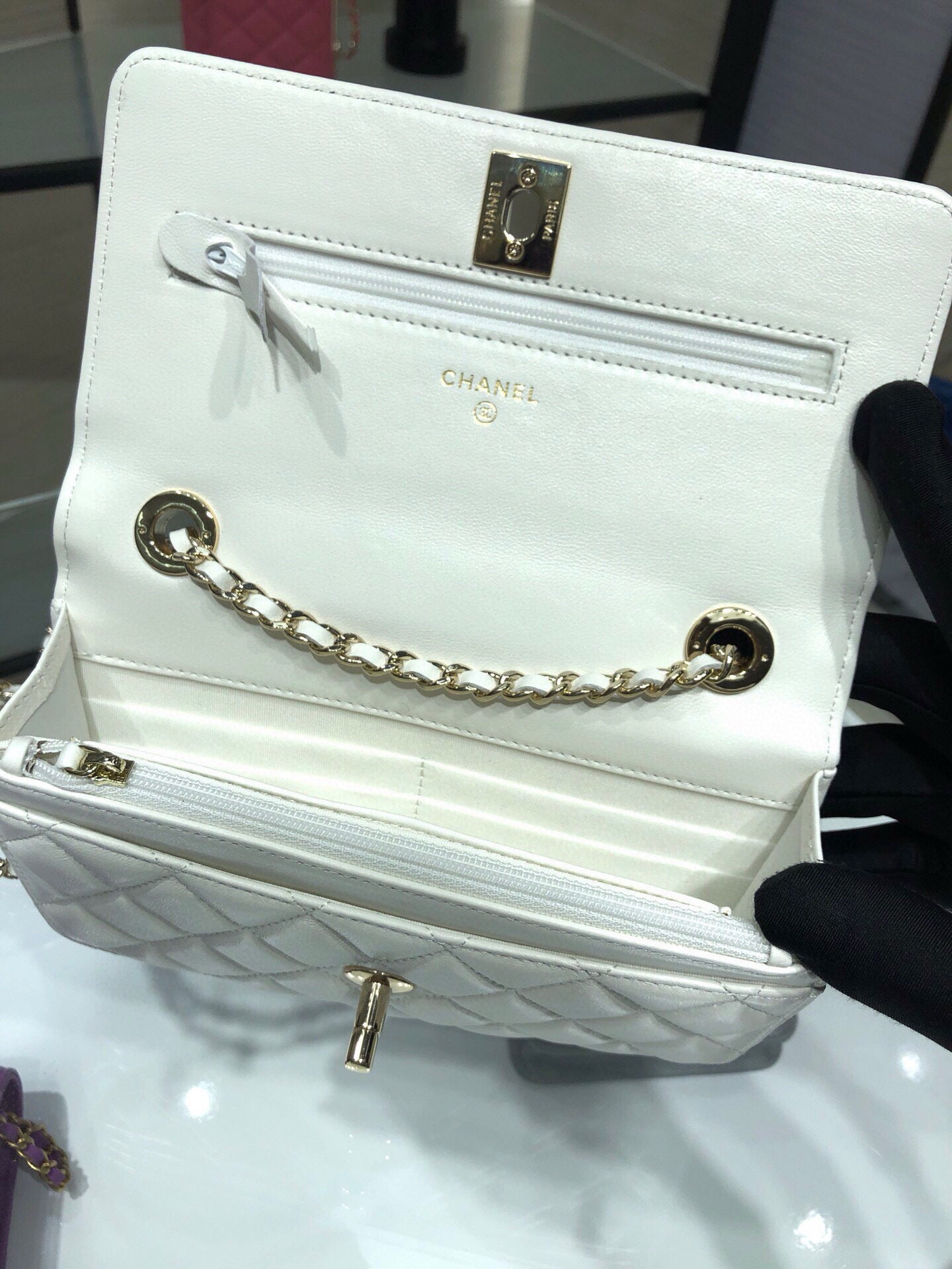 White leather flap bag with gold chain strap, front pocket, and CHANEL logo hardware
