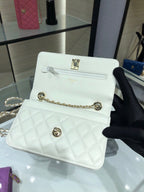 White quilted flap bag with gold chain strap and front turn-lock logo, close-up
