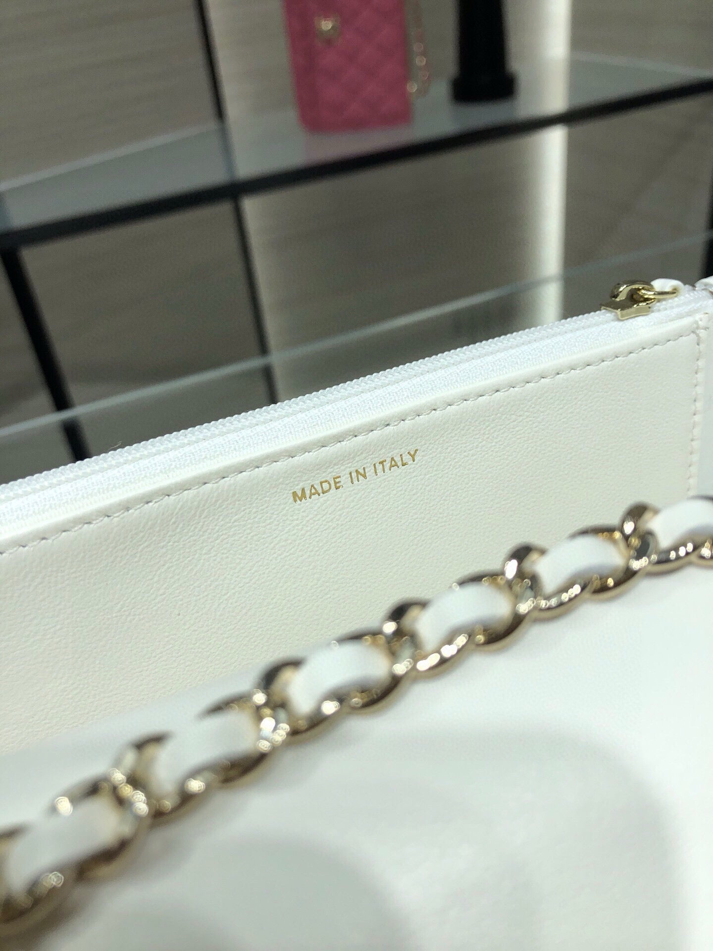 White leather bag detail showing 'MADE IN ITALY' stamp and gold chain link
