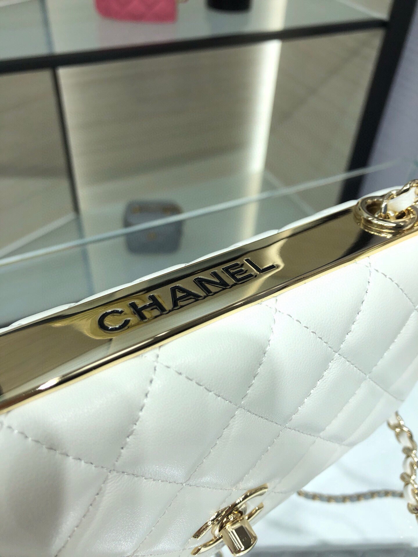 White quilted flap bag with gold CHANEL logo bar clasp and chain strap