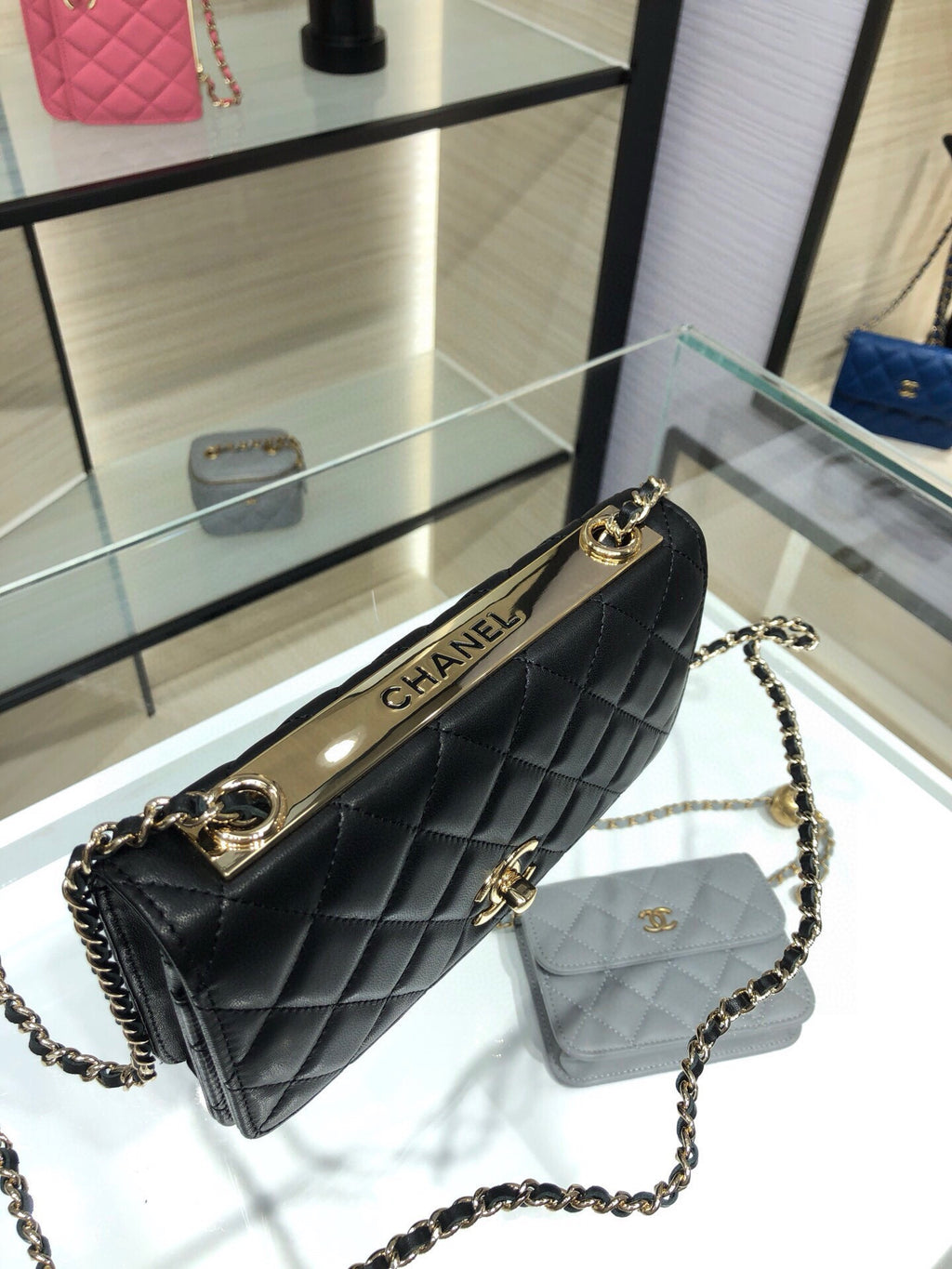 Black quilted mini bag with chain strap and gold CHANEL lettering on trim