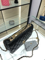 Black quilted mini bag with chain strap and gold CHANEL lettering on trim