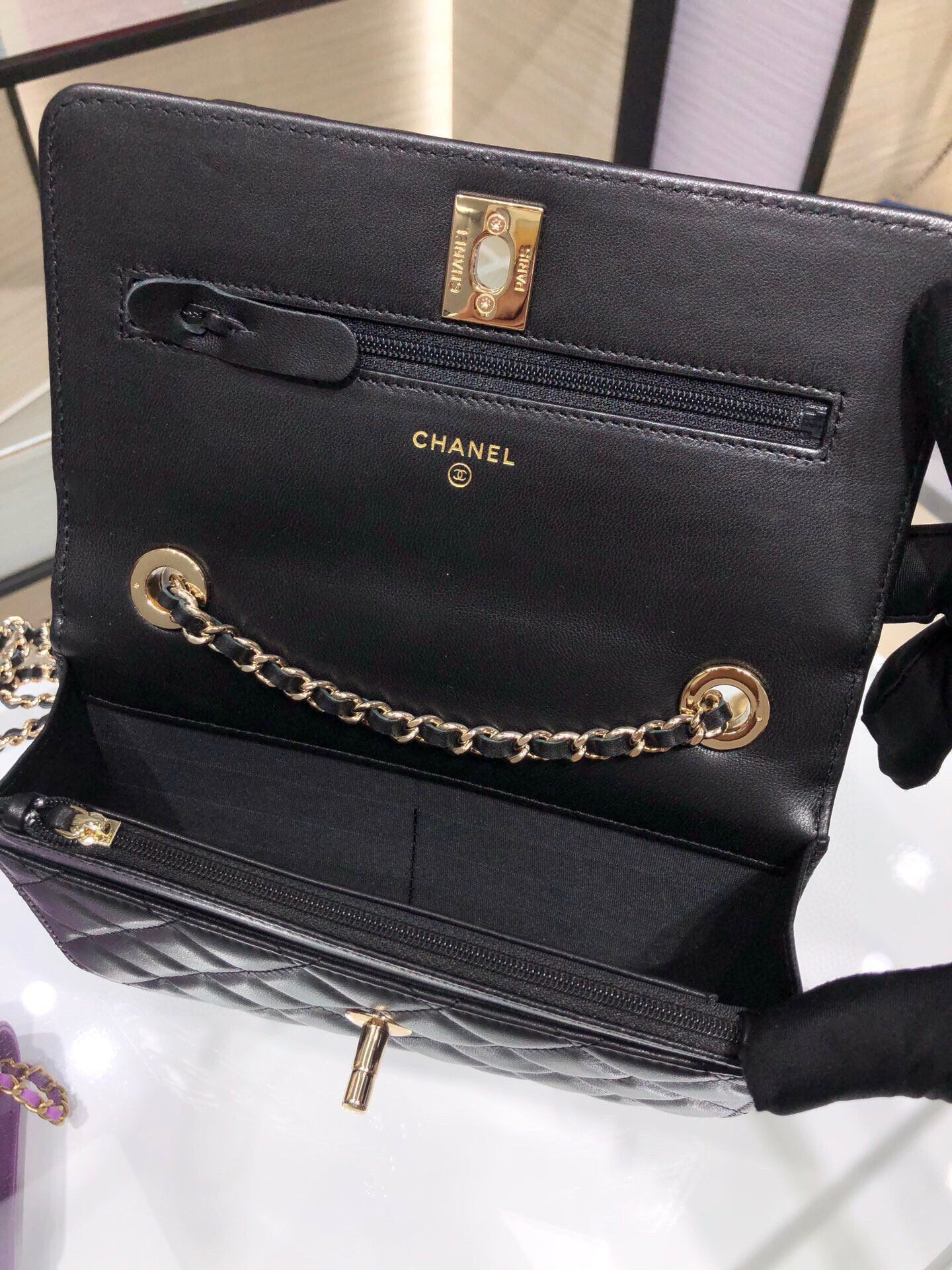 Black leather Chanel shoulder bag with gold clasp, logo, and chain strap