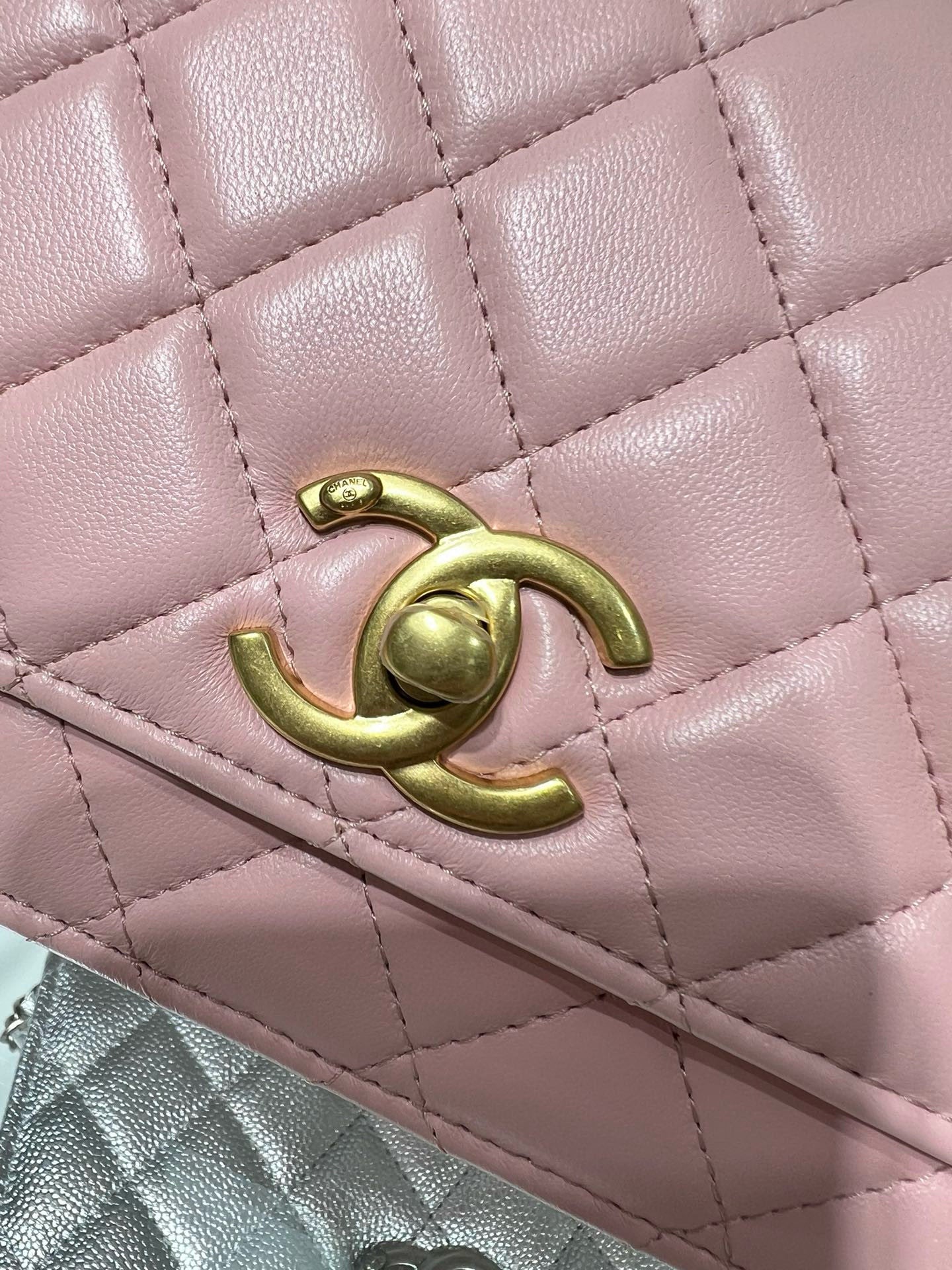 Close-up of pink quilted Chanel bag with gold CC emblem and seam stitching