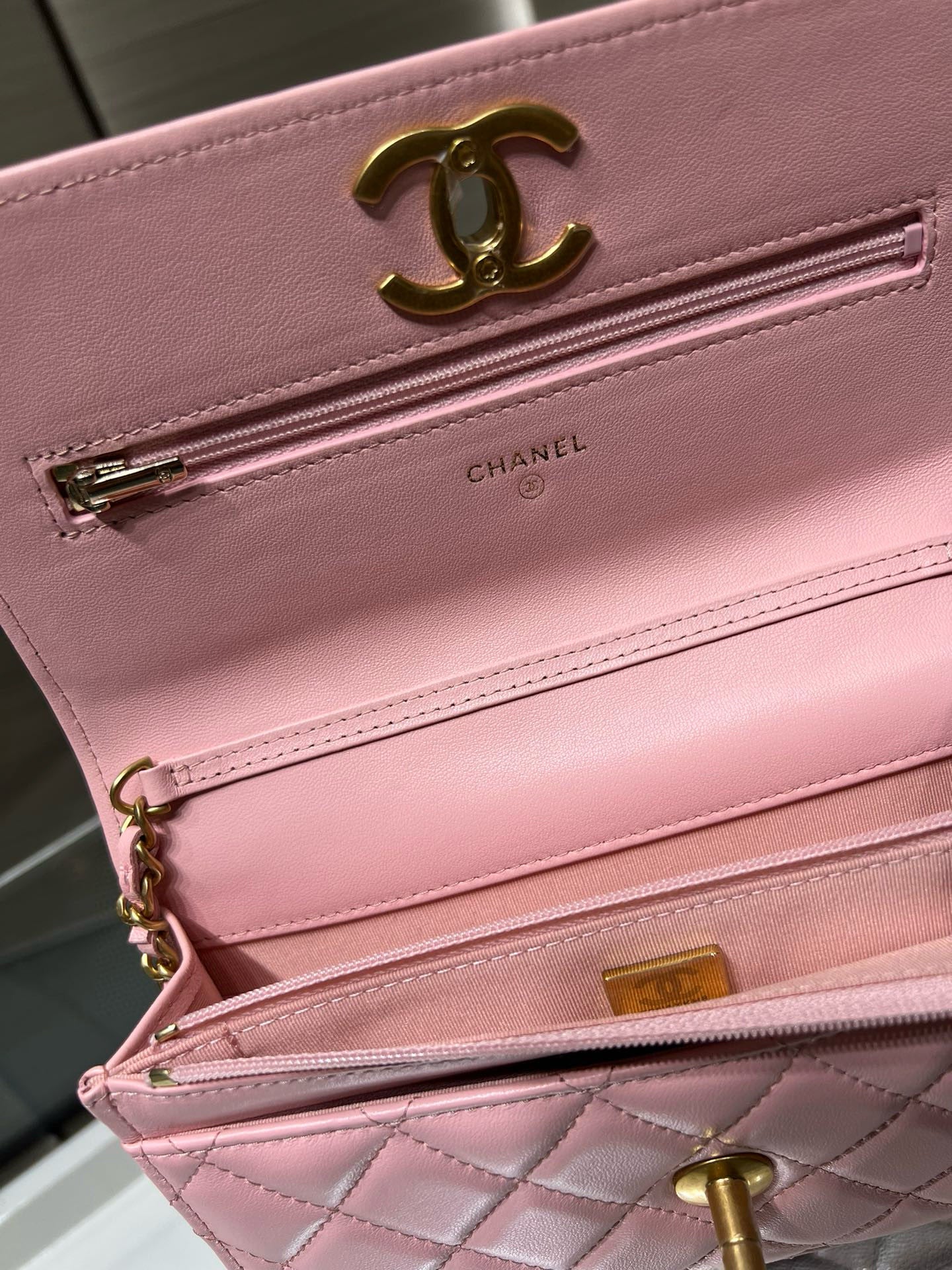 Chanel pink quilted bag close-up of gold-tone zipper, logo hardware, interior