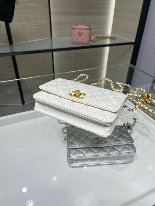 White quilted Chanel flap bag with gold hardware, plus a silver quilted bag beside it