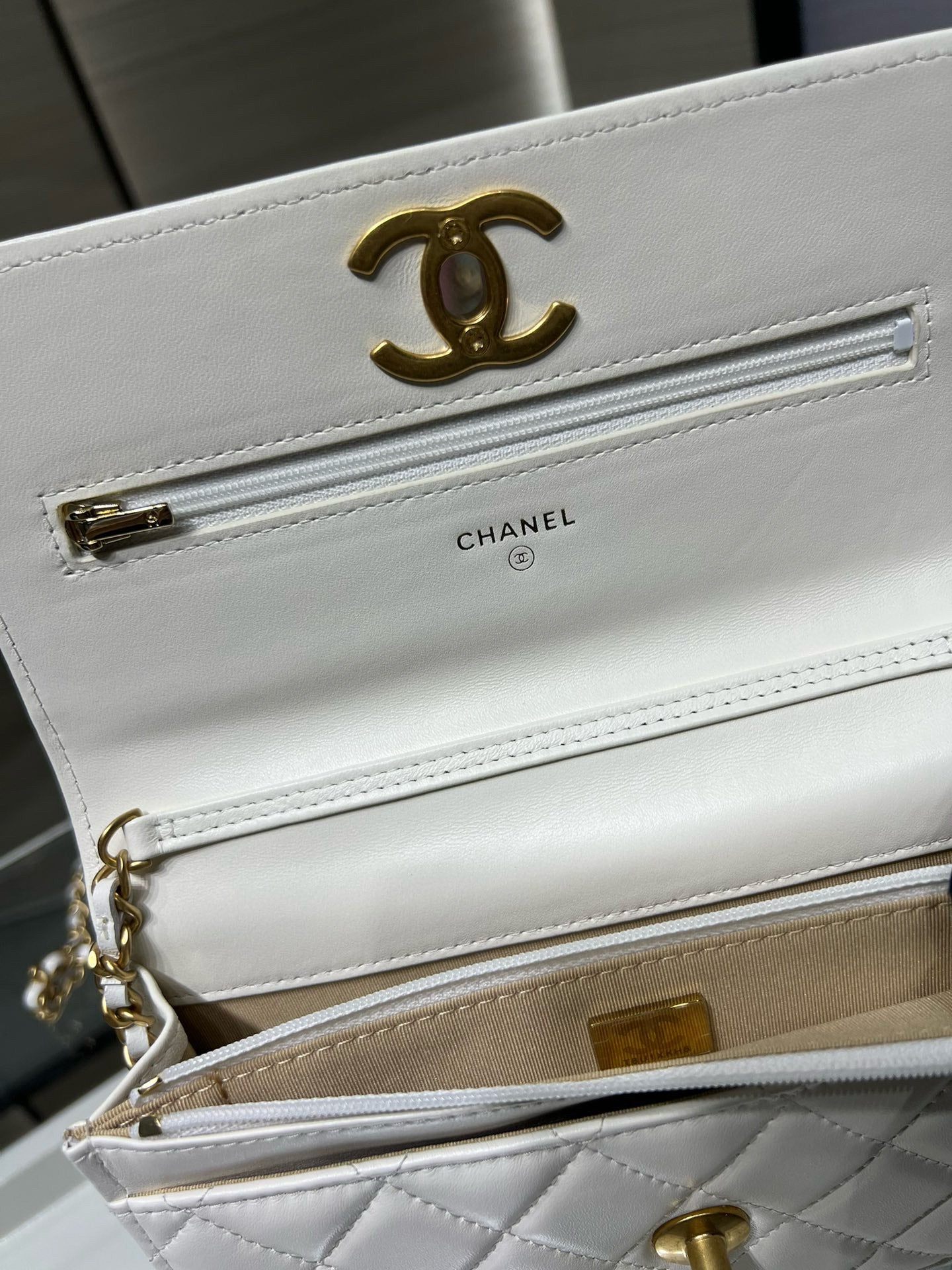 White Chanel bag interior detail with CC logo, chain, and credit-card slot