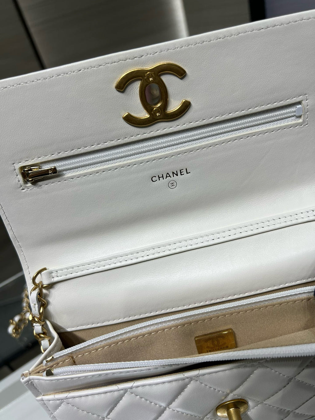 White leather flap bag with gold Chanel logo, front pocket zip and chain strap.