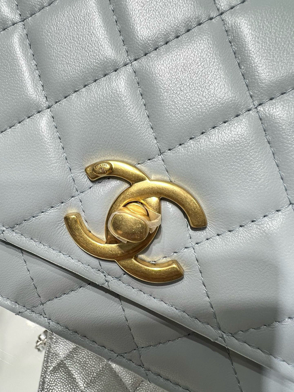 Chanel quilted bag close-up with gold CC logo on light blue leather