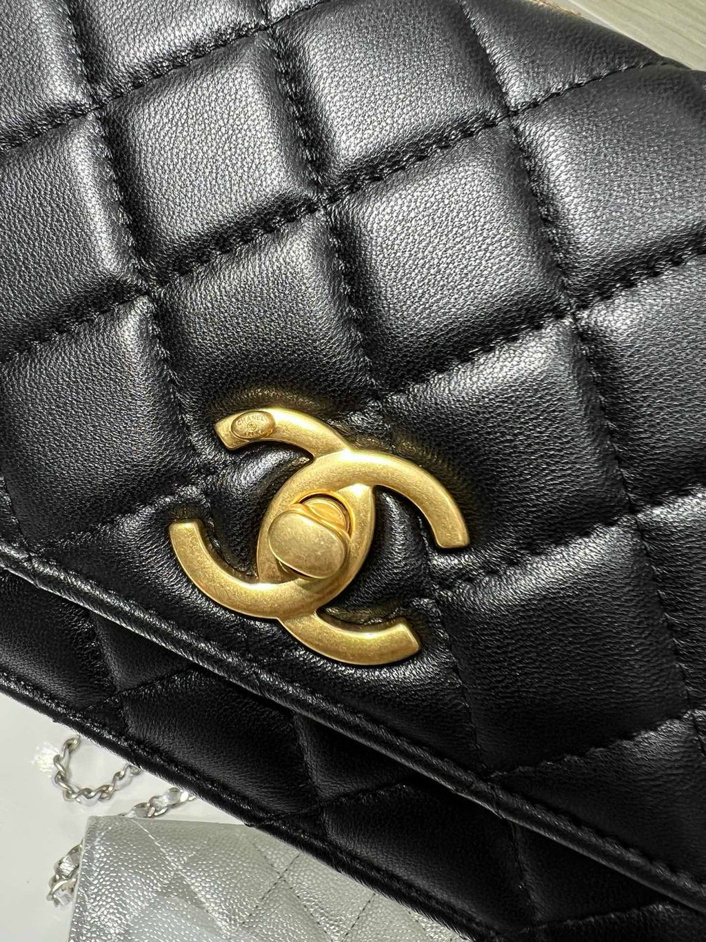 Close-up quilted black Chanel bag with gold-tone interlocking CC logo