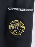 Versace black jogger pants with gold medallion emblem on front pocket.