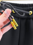 Versace black jogger pants close-up of drawstring cord and gold tips.