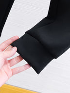 Black sweatpant cuff and fabric fold detail with hand showing drape