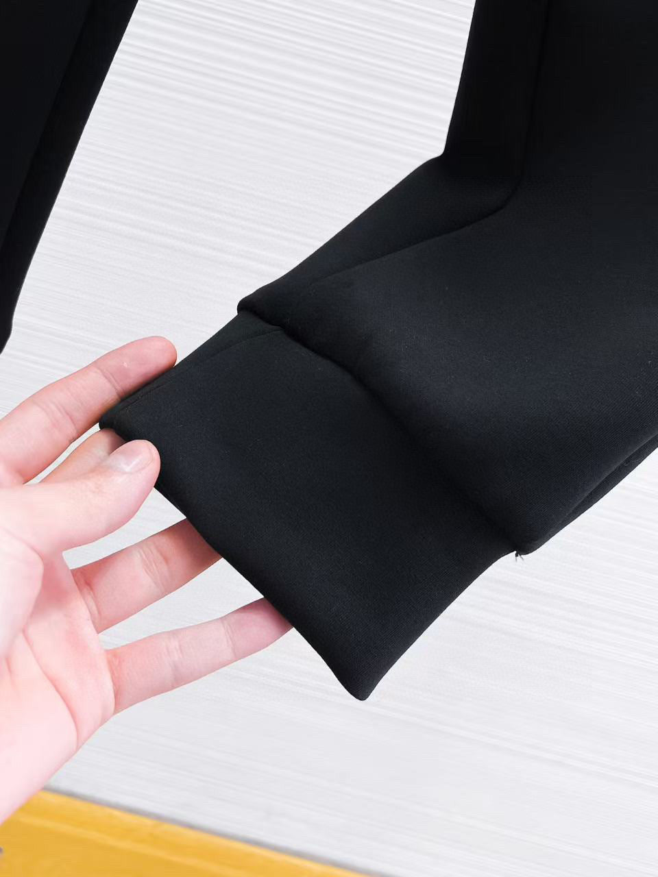 Versace black jogger pants cuff and side seam close-up held by hand.