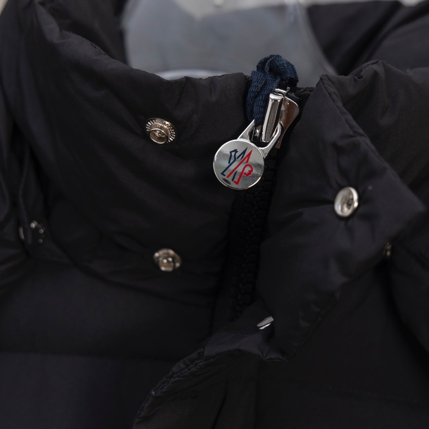 Moncler long puffer jacket chest logo and snap buttons on dark fabric