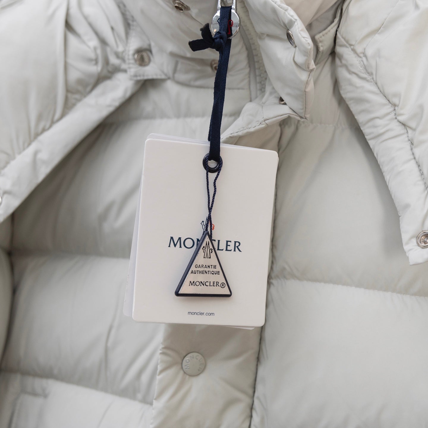 White puffer jacket with hanging logo tag and padded quilted lining