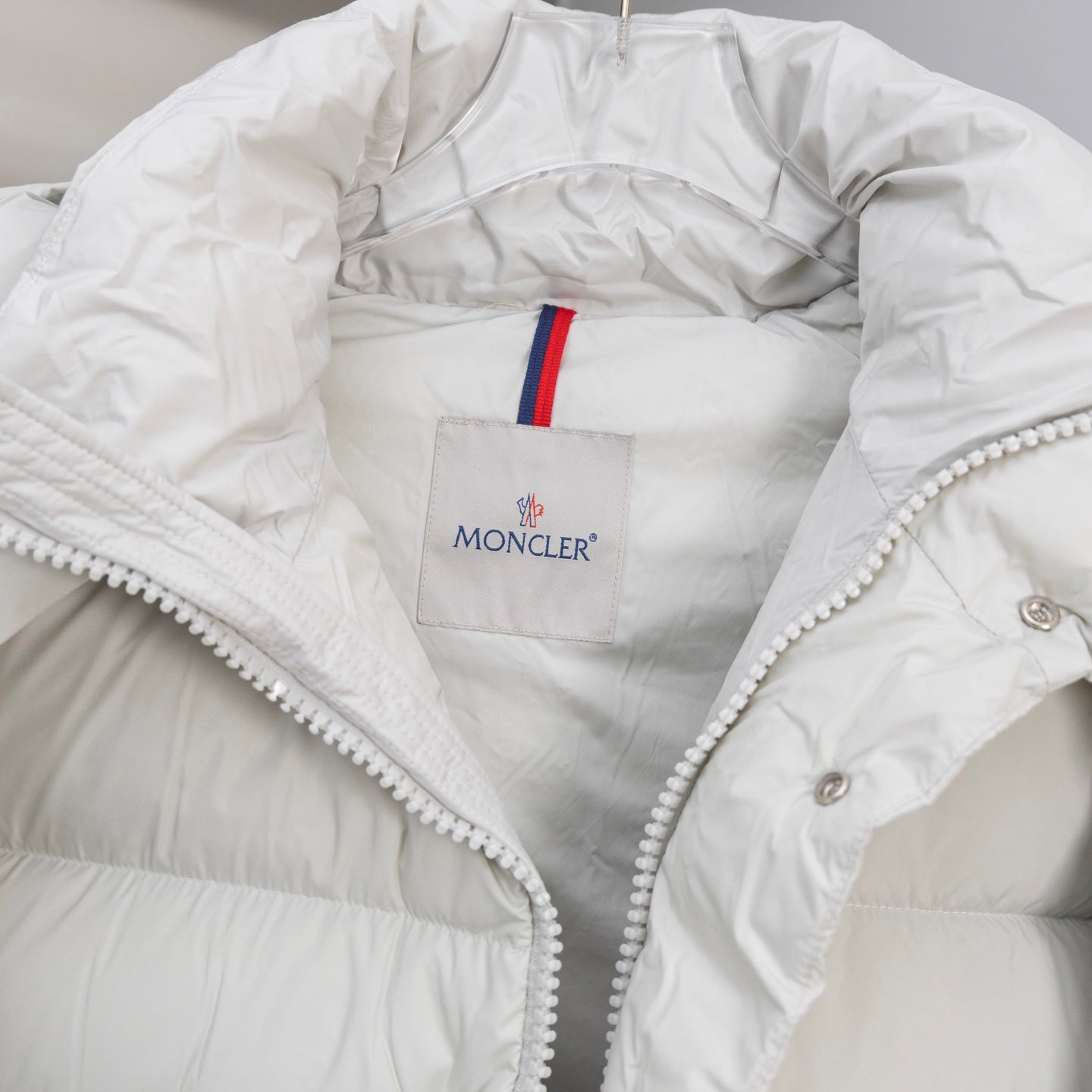 White puffer jacket with Moncler chest logo patch and striped zipper tape