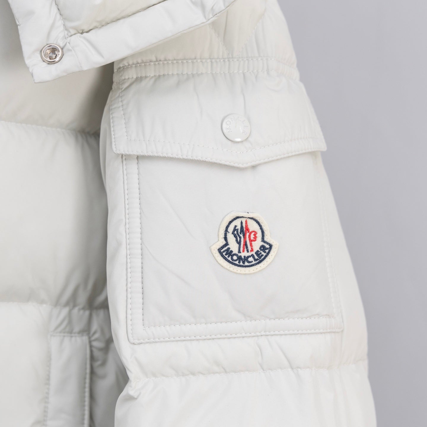 White puffer jacket front flap pocket with circular logo patch