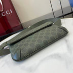Gucci bag with GG monogram canvas, green, laid on table with long strap.