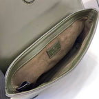 Gucci bag interior detail with metal logo plaque and green-trim lining.